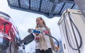 Female driver powers up EV at roadside charging station