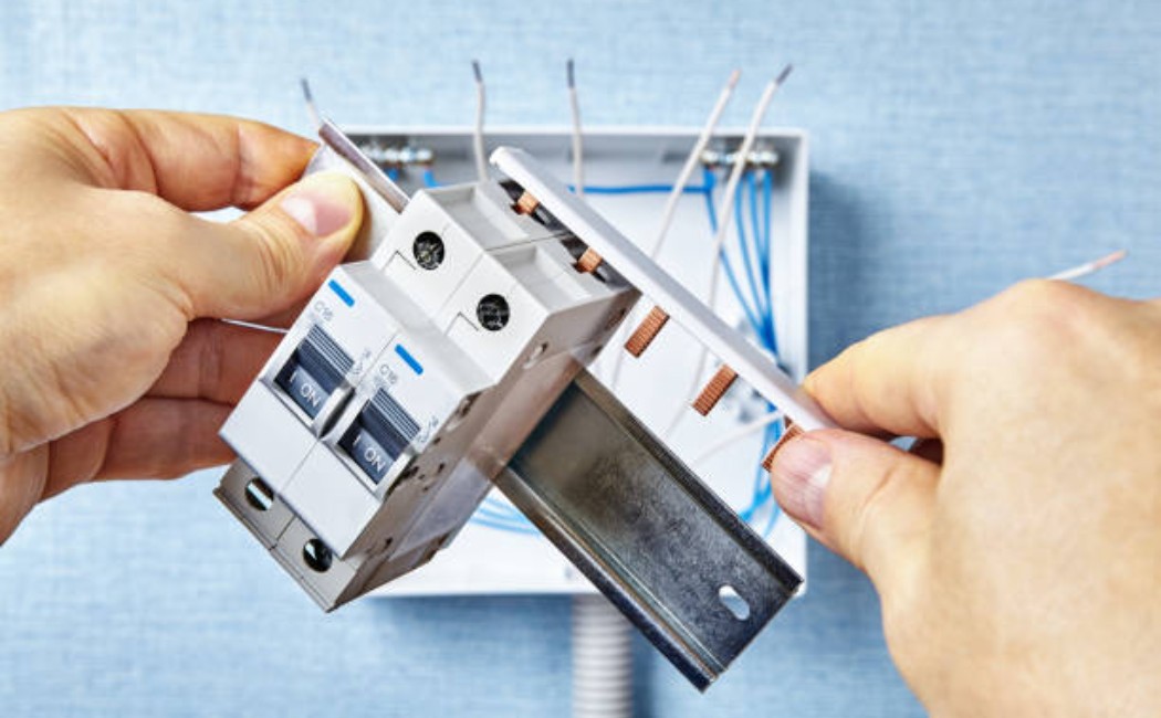 Electrical technician working on circuit breaker connections.