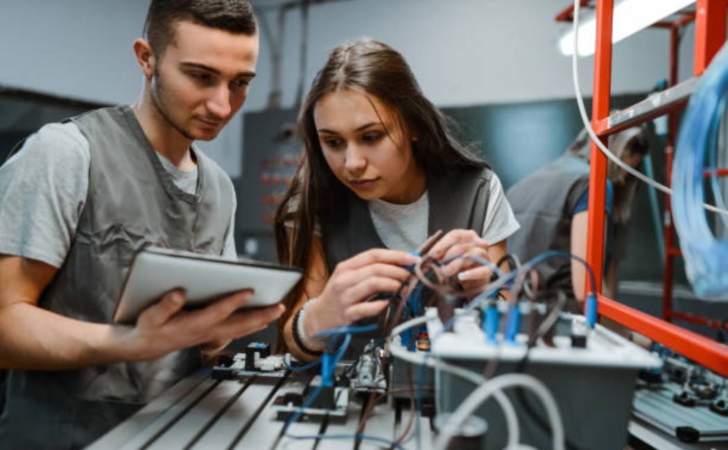 Engineering learners examining wiring diagrams for PLC installation.
