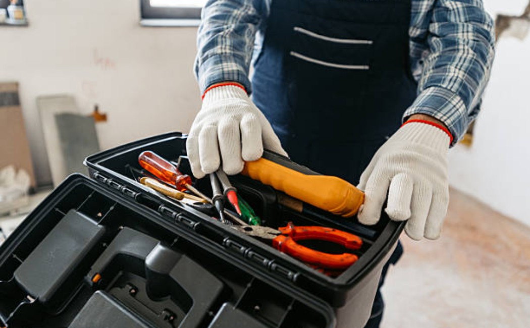 Senior electrician placing a multimeter into a toolbox in an empty apartment.