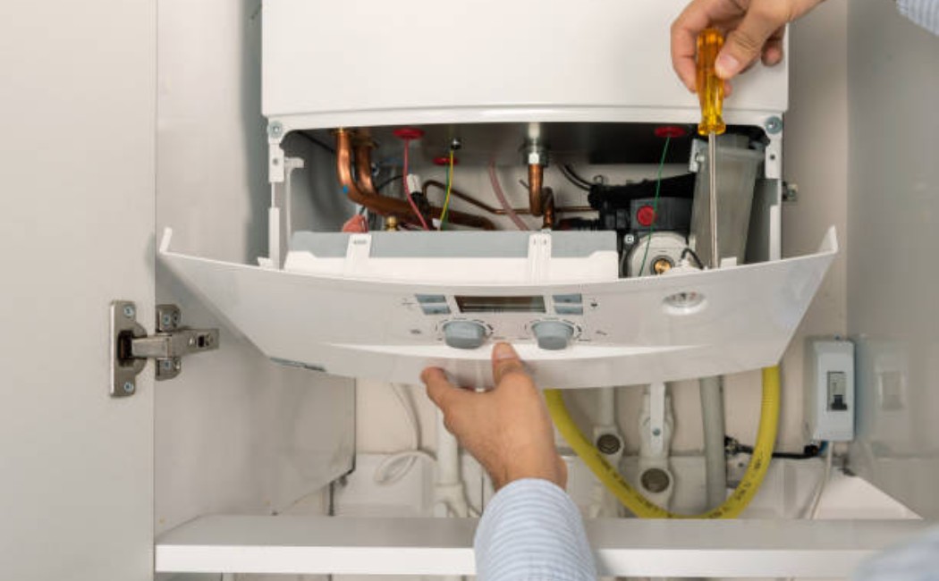 A professional fixing a residential gas boiler unit indoors.