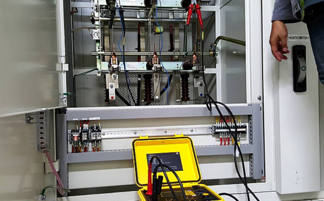 Worker checking insulation resistance of electrical switch.